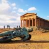 a statue beside a concrete acropolis