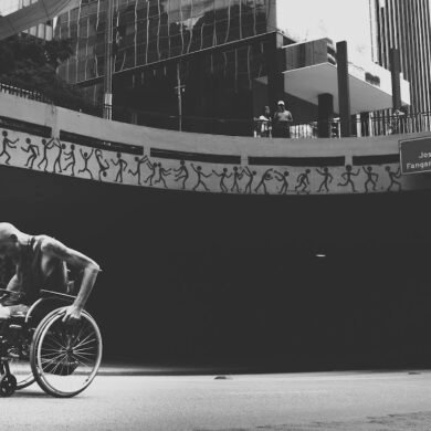 grayscale photo of man on wheelchair