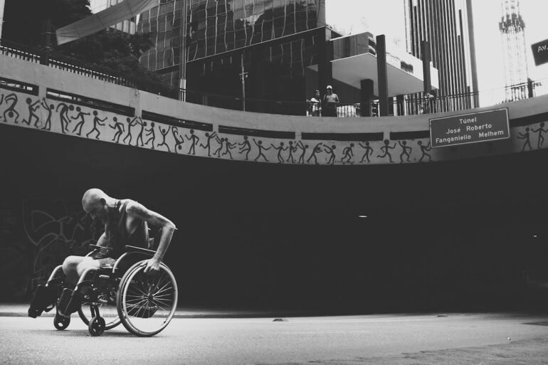 grayscale photo of man on wheelchair