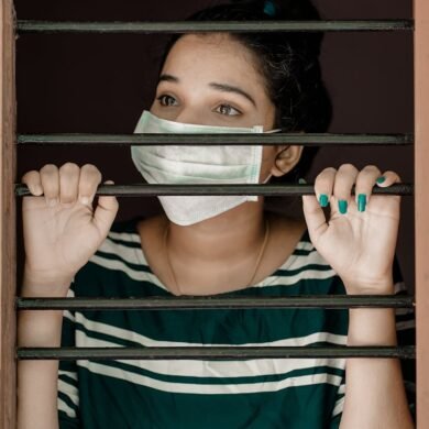 woman in green and white stripe shirt covering her face with white mask