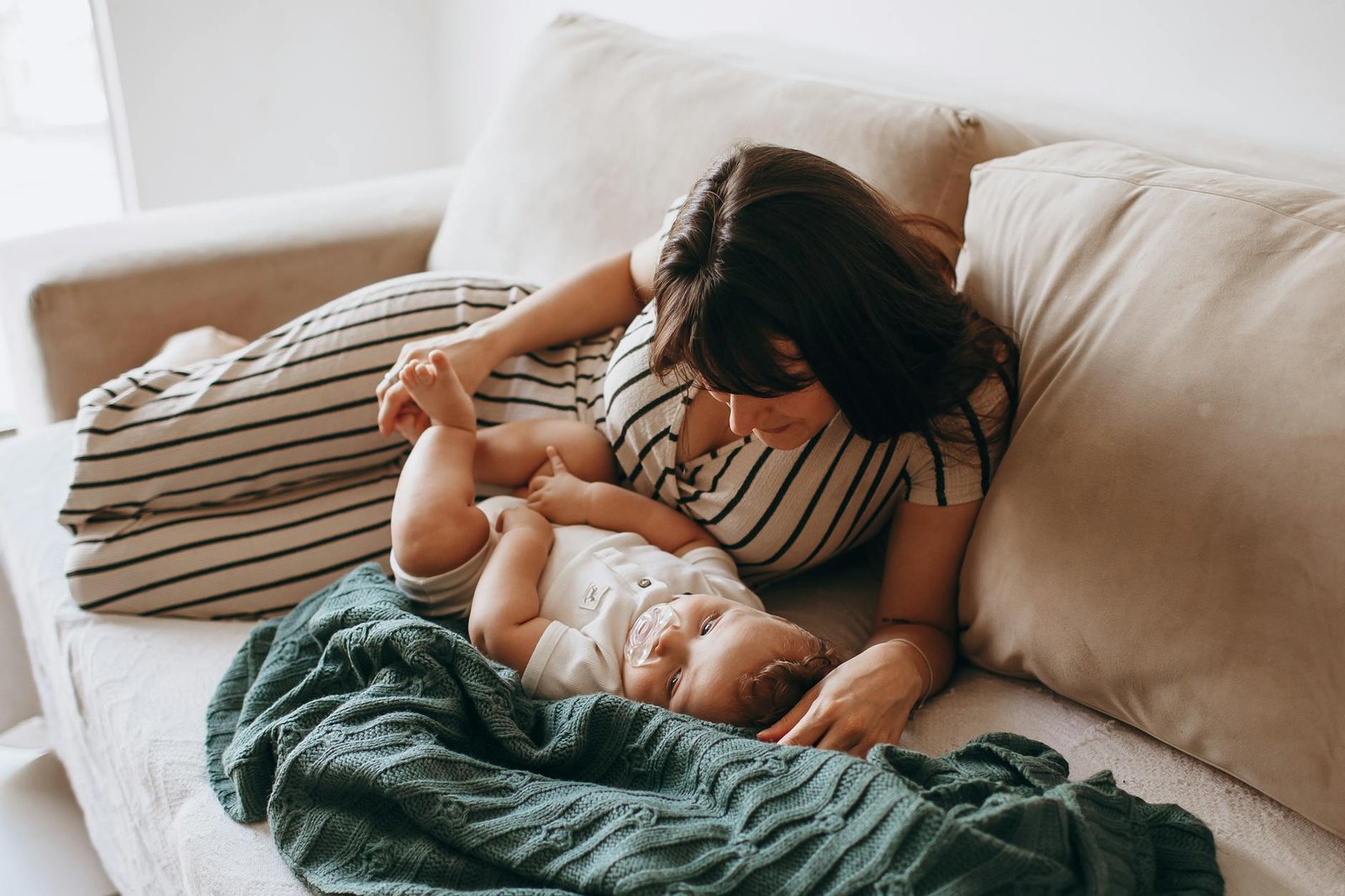 a woman and her baby laying on a couch